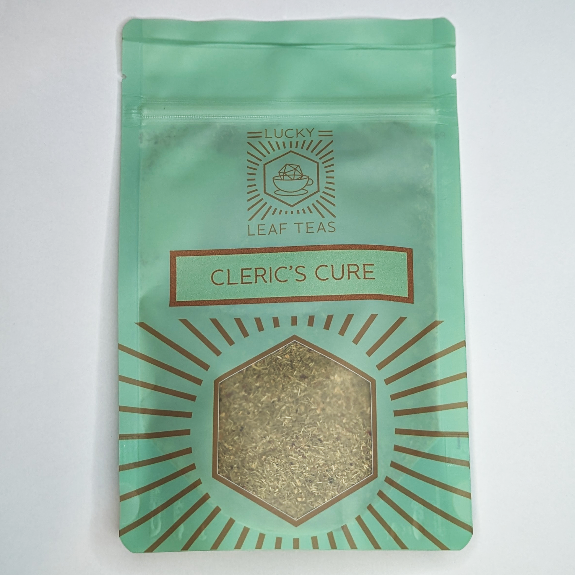 A mint-green package containing 50g of Cleric’s Cure: a herbal infusion blend. The name is stickered on the front, below the Lucky Leaf Teas Logo and above a hexagonal window displaying the tea.