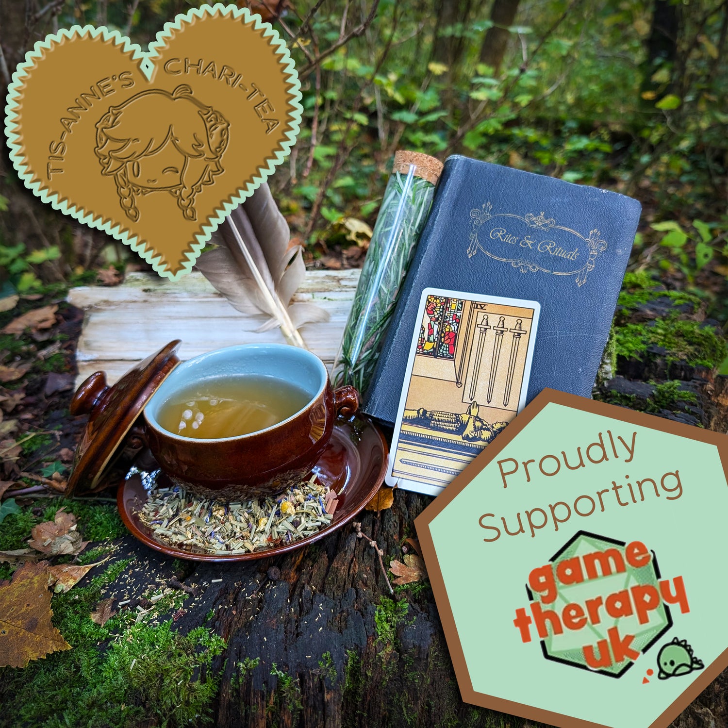 A brown-glazed bowl filled with a clear, amber-yellow liquid. It sits on a matching saucer, which has a scattering of leaves and flowers upon it. To the right is a "Four of Swords" tarot card, a pair of feathers, a corked vial filled with a fresh herb, and a blue book titled "Rites and Rituals."
A heart-shaped badge in one corner reads "Tis-Anne's Chari-Tea", and an emblem in the other reads "Proudly Supporting Game Therapy UK"