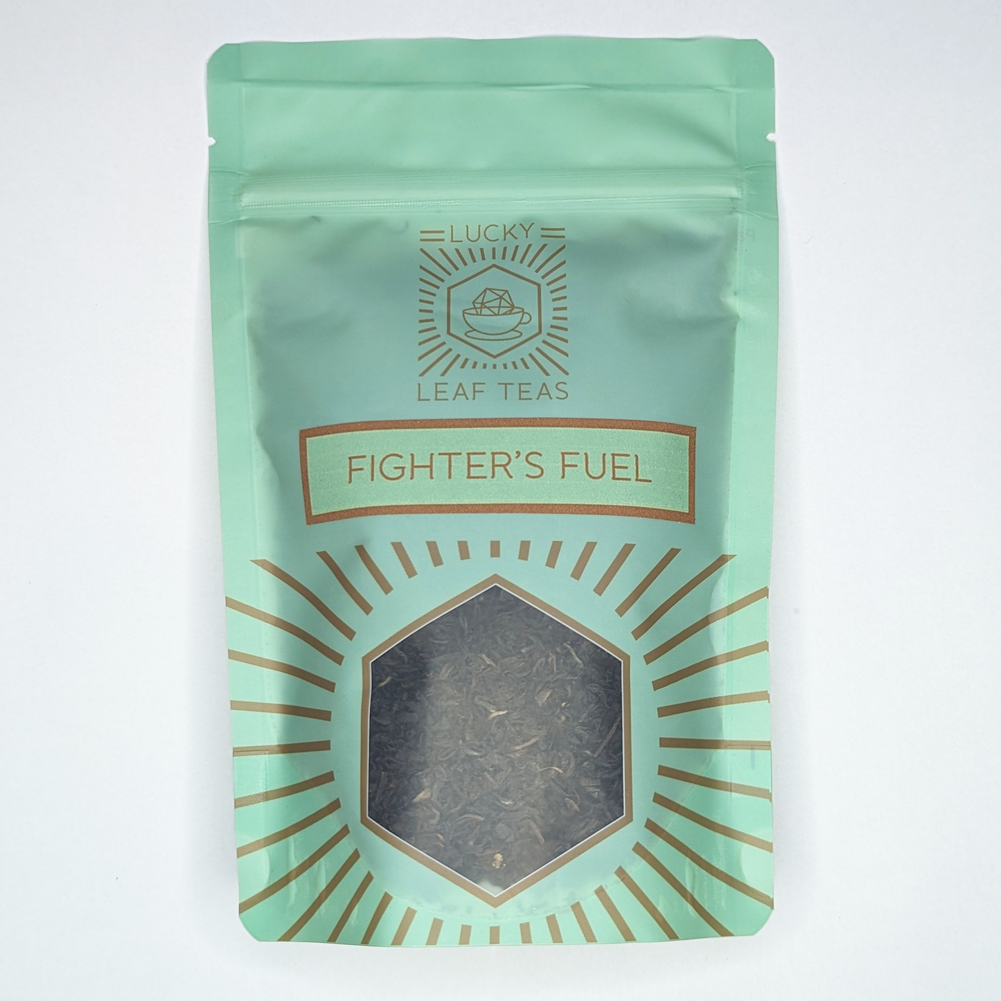 A mint-green package containing 100g of Fighter’s Fuel: a black tea blend. The name is stickered on the front, below the Lucky Leaf Teas Logo and above a hexagonal window displaying the tea.