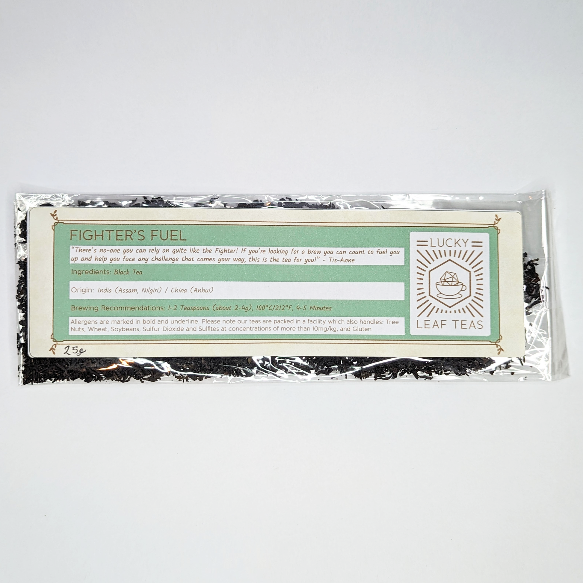A slim, see-through package containing 25g of Fighter’s Fuel: a black tea blend. A label with the name, ingredients, origin and brewing recommendations is printed on the front, next to the Lucky Leaf Teas Logo.