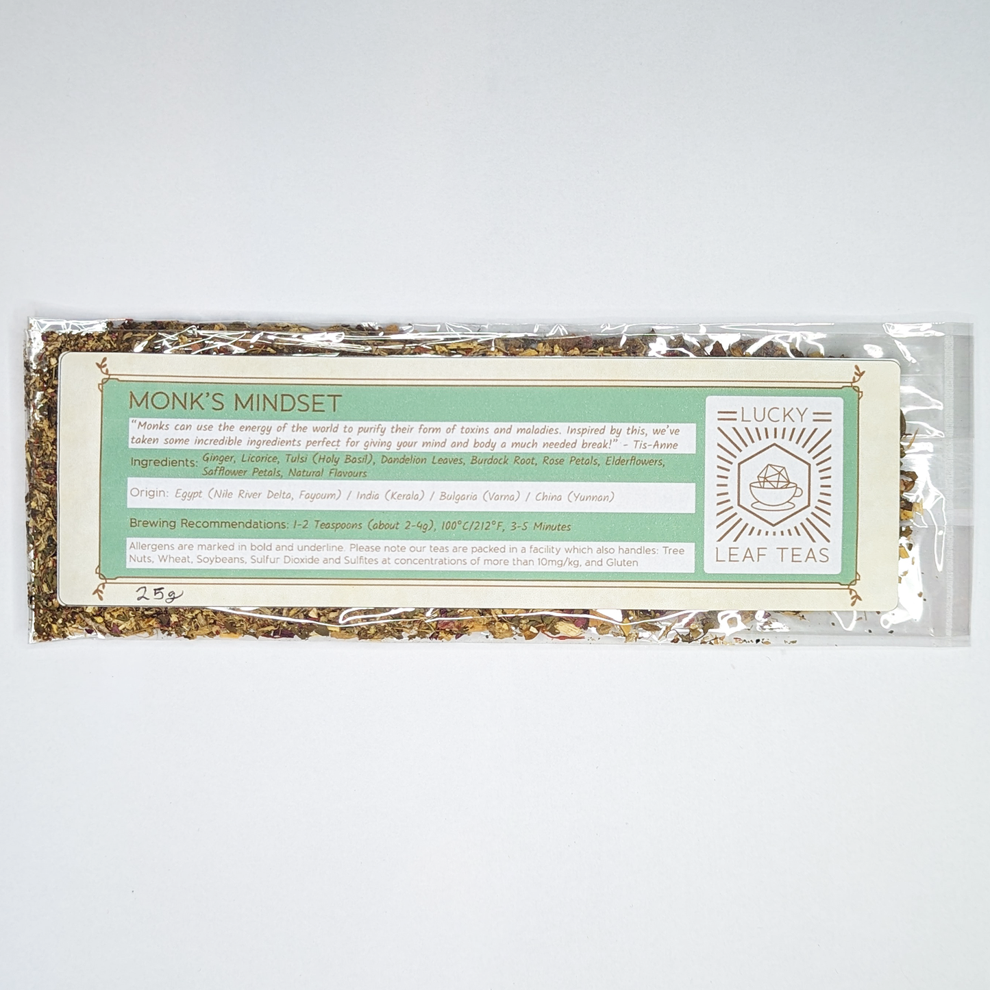 A slim, see-through package containing 25g of Monk’s Mindset: an infusion blend of herbs and flowers. A label with the name, ingredients, origin and brewing recommendations is printed on the front, next to the Lucky Leaf Teas Logo.