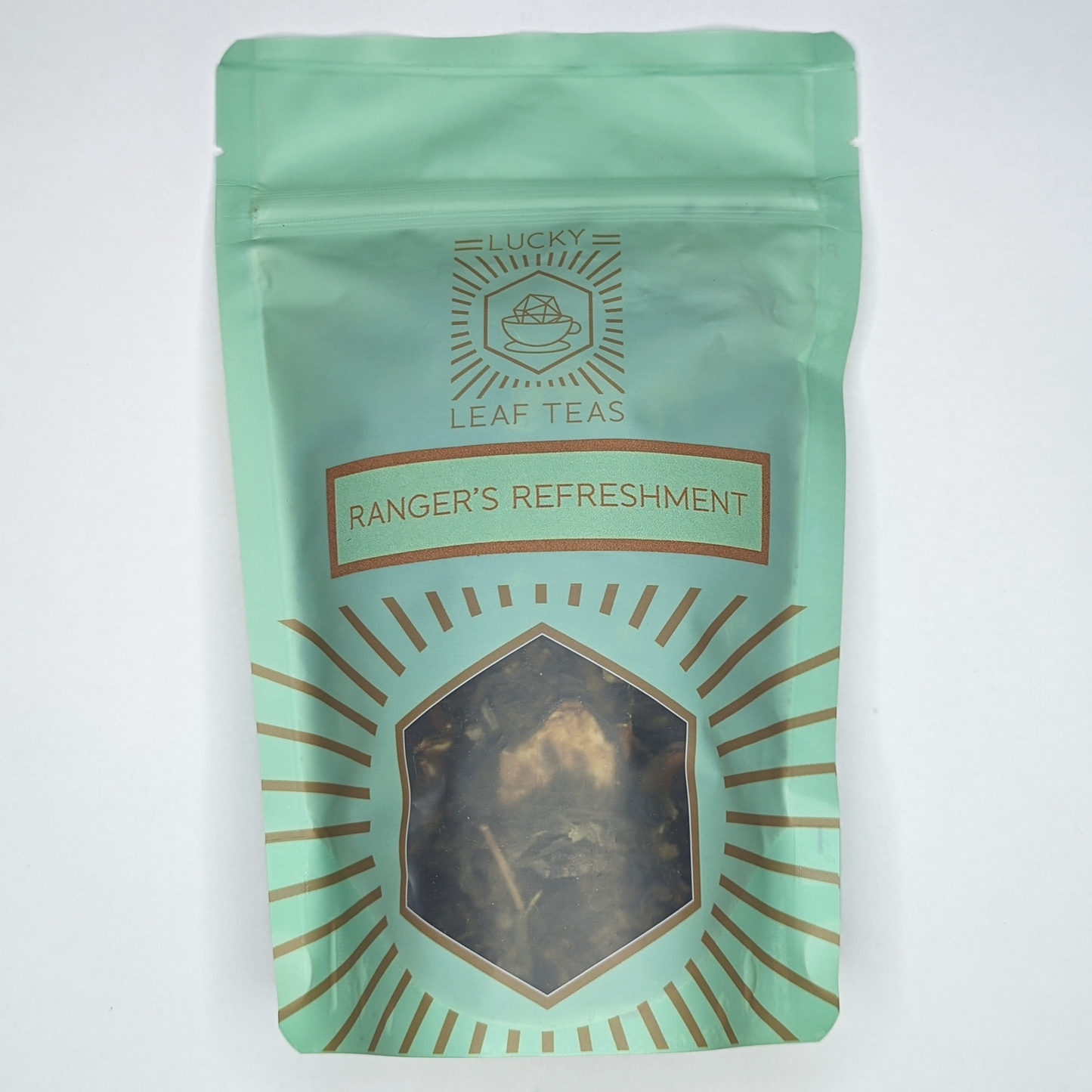 A mint-green package containing 100g of Ranger’s Refreshment: a green tea blend with visible dried cucumber slices. The name is stickered on the front, below the Lucky Leaf Teas Logo and above a hexagonal window displaying the tea.