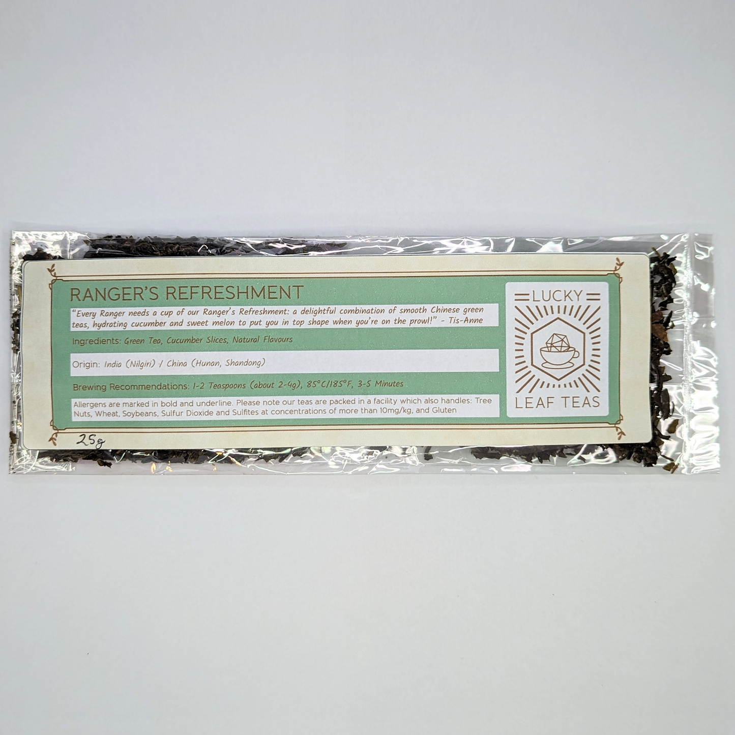 A slim, see-through package containing 25g of Ranger’s Refreshment: a green tea blend with visible dried cucumber slices. A label with the name, ingredients, origin and brewing recommendations is printed on the front, next to the Lucky Leaf Teas Logo.