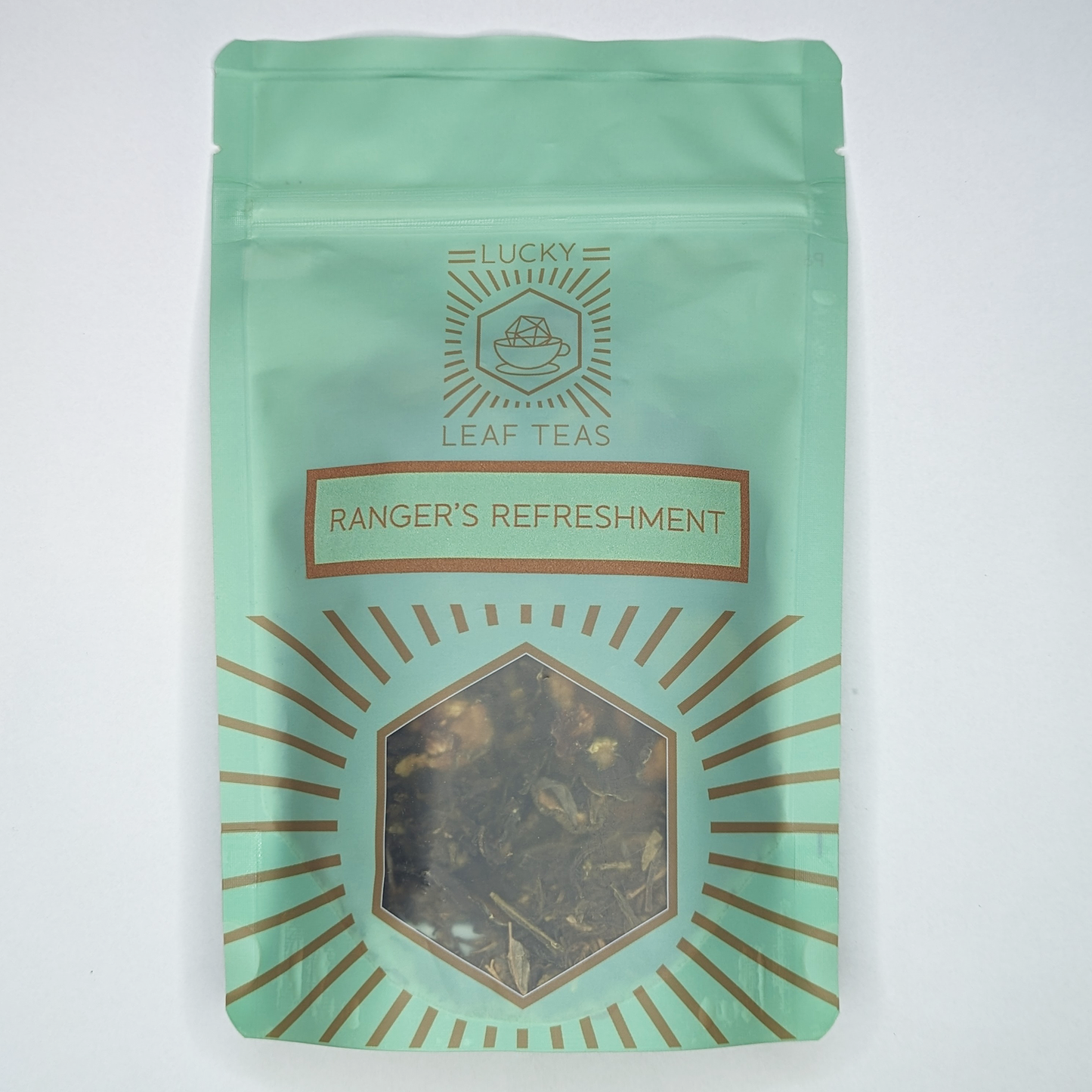 A mint-green package containing 50g of Ranger’s Refreshment: a green tea blend with visible dried cucumber slices. The name is stickered on the front, below the Lucky Leaf Teas Logo and above a hexagonal window displaying the tea.