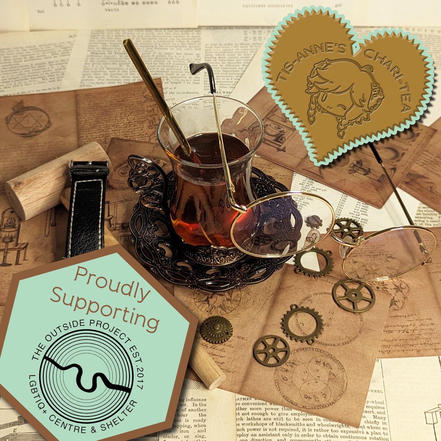 A tall, glass cup of tea and a wrought-iron dish are on top of sheets of paper covered in alchemical and engineering designs.
A heart-shaped badge in one corner reads "Tis-Anne's Chari-Tea", and an emblem in the other reads "Proudly Supporting The Outside Project - LGBTIQ+ Centre & Shelter - Est. 2017."