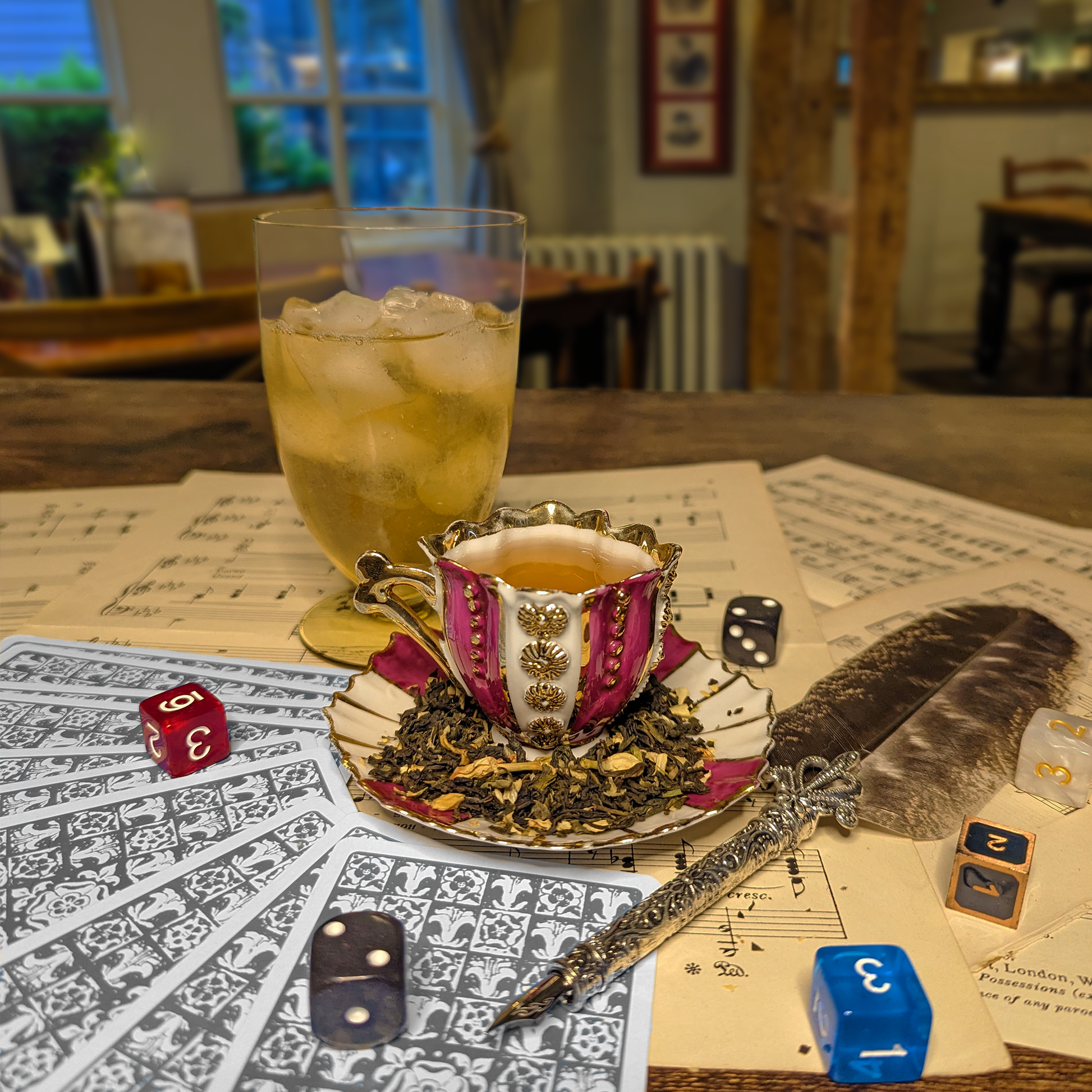 A striped and gilded teacup and saucer, next to a glass of iced tea, an elegant quill and sheet music.