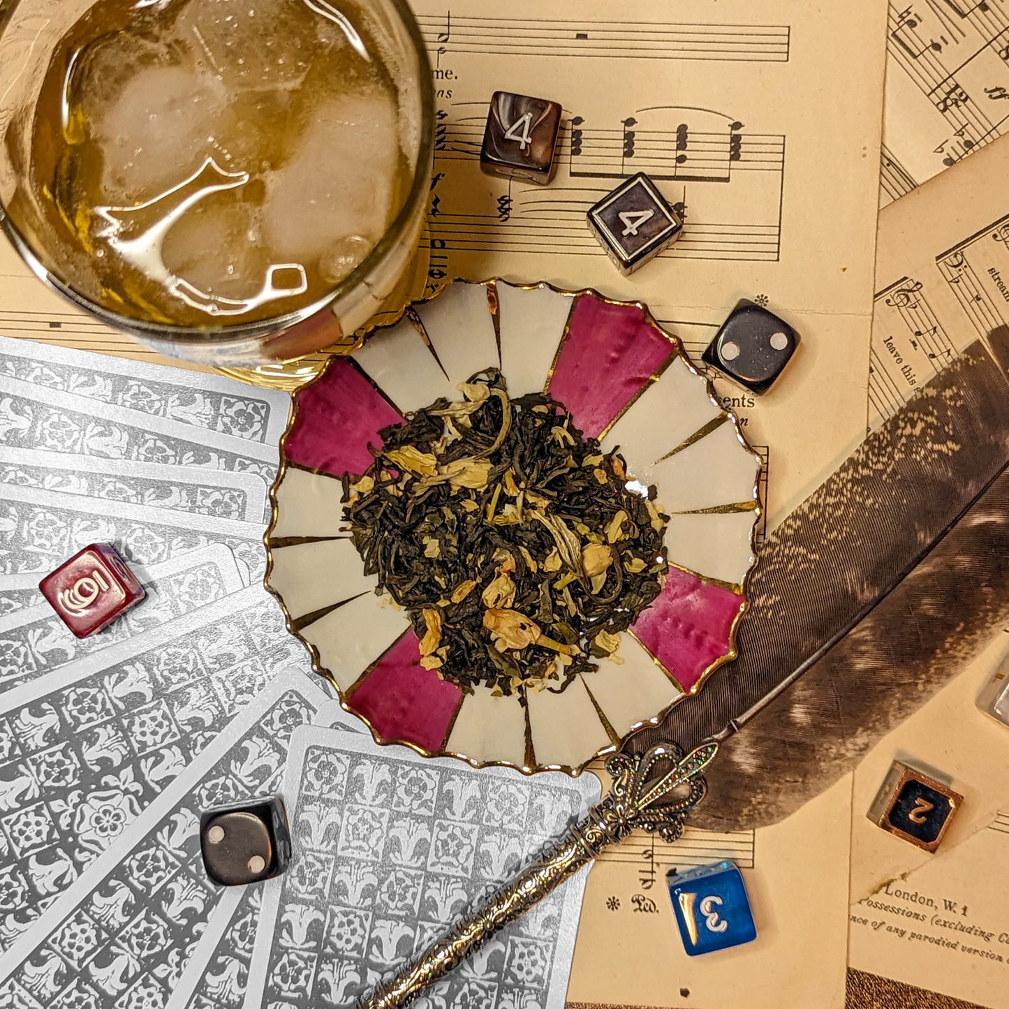 A gold-edged striped saucer, with a handful of tea leaves in the center, which are mixed with lots of jasmine flowers and petals.