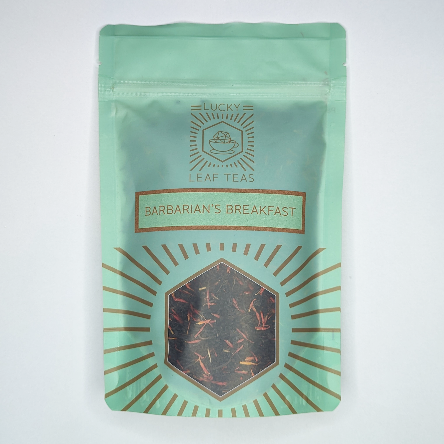 A mint-green package containing 100g of Barbarian's Breakfast: a black tea blend with visible red safflower petals. The name is stickered on the front, below the Lucky Leaf Teas Logo and above a hexagonal window displaying the tea.