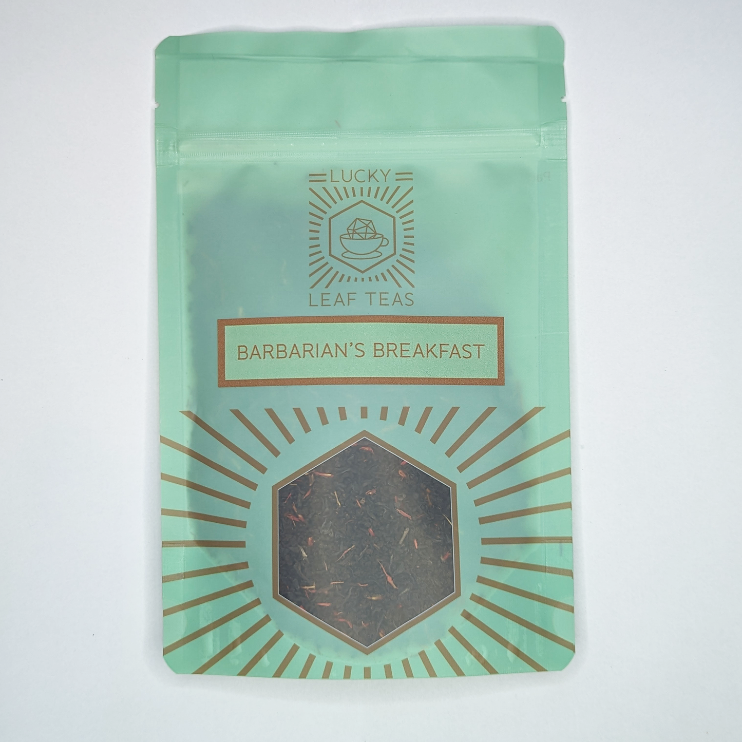 A mint-green package containing 50g of Barbarian's Breakfast: a black tea blend with visible red safflower petals. The name is stickered on the front, below the Lucky Leaf Teas Logo and above a hexagonal window displaying the tea.