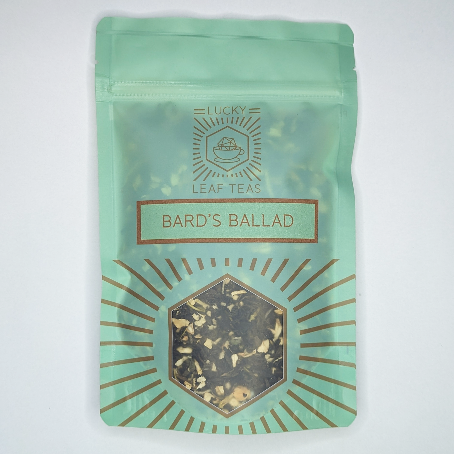 A mint-green package containing 50g of Bard’s Ballad: a green tea blend with visible jasmine flowers. The name is stickered on the front, below the Lucky Leaf Teas Logo and above a hexagonal window displaying the tea.