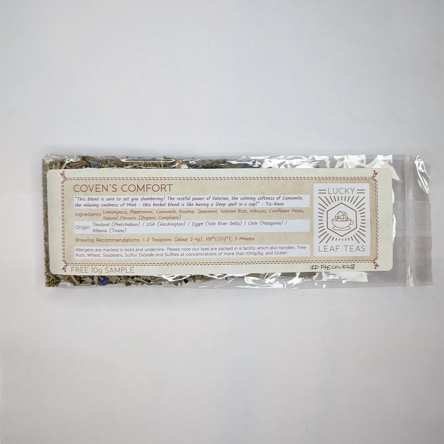 A slim, see-through package containing 25g of Coven's Comfort: a herbal infusion. A label with the name, ingredients, origin and brewing recommendations is printed on the front, next to the Lucky Leaf Teas Logo.