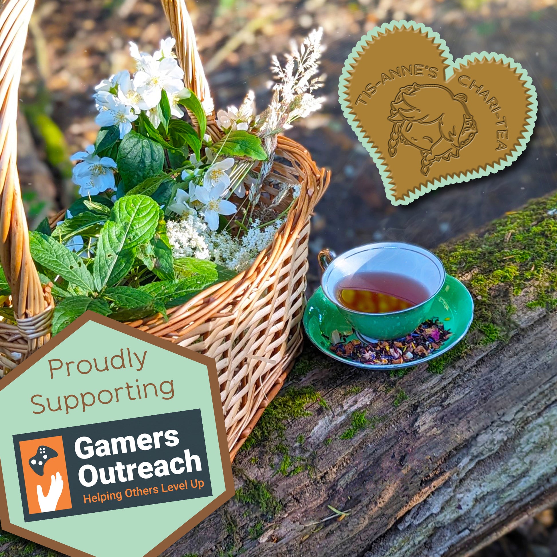 A green teacup and saucer on  a mossy log, next to a basket of wildflowers and leaves. A heart-shaped badge in one corner reads "Tis-Anne's Chari-Tea", and another emblem reads "Proudly Supporting" with the logo for Gamers Outreach.