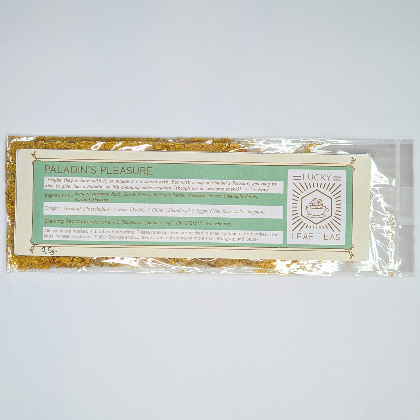 A slim, see-through package containing 25g of Paladin’s Pleasure: a bright yellow infusion blend of spices, fruits and flowers. A label with the name, ingredients, origin and brewing recommendations is printed on the front, next to the Lucky Leaf Teas Logo.