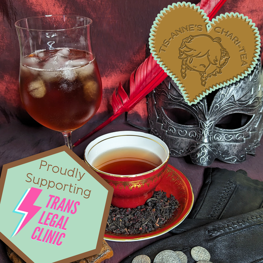 A red teacup and saucer next to a wine glass, both filled with copper red tea, one hot, one iced. A small pile of tea leaves fill the saucer. Behind sits a red quill pen and a silver masquerade mask. In front, a pair of gloves, silver coins and a set of rusty keys.
A heart-shaped badge in one corner reads "Tis-Anne's Chari-Tea", and an emblem in the other reads "Proudly Supporting - Trans Legal Clinic."