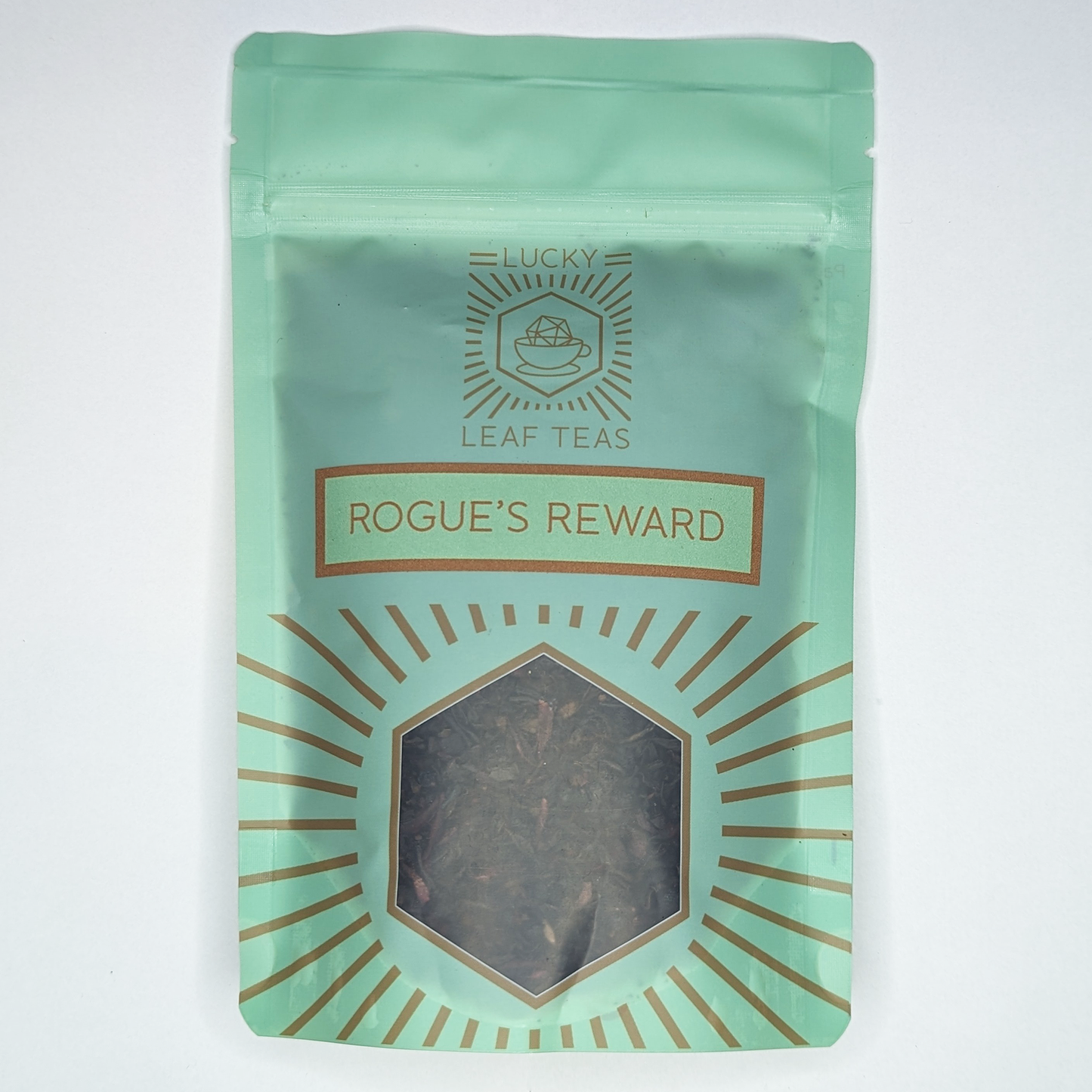 A mint-green package containing 100g of Rogue’s Reward: a black tea blend with visible dried berries and hibiscus petals. The name is stickered on the front, below the Lucky Leaf Teas Logo and above a hexagonal window displaying the tea.