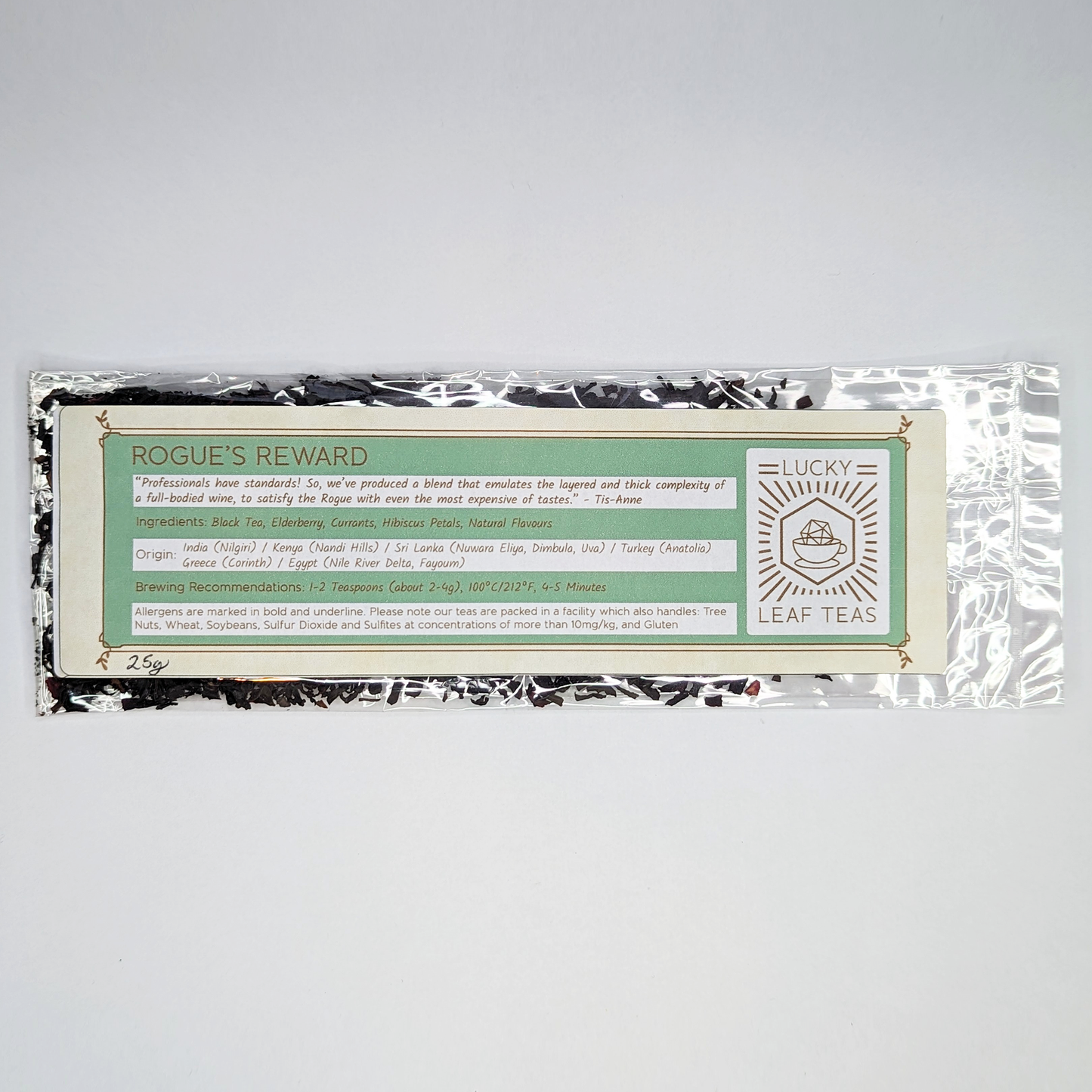 A slim, see-through package containing 25g of Rogue’s Reward: a black tea blend with visible dried berries and hibiscus petals. A label with the name, ingredients, origin and brewing recommendations is printed on the front, next to the Lucky Leaf Teas Logo.