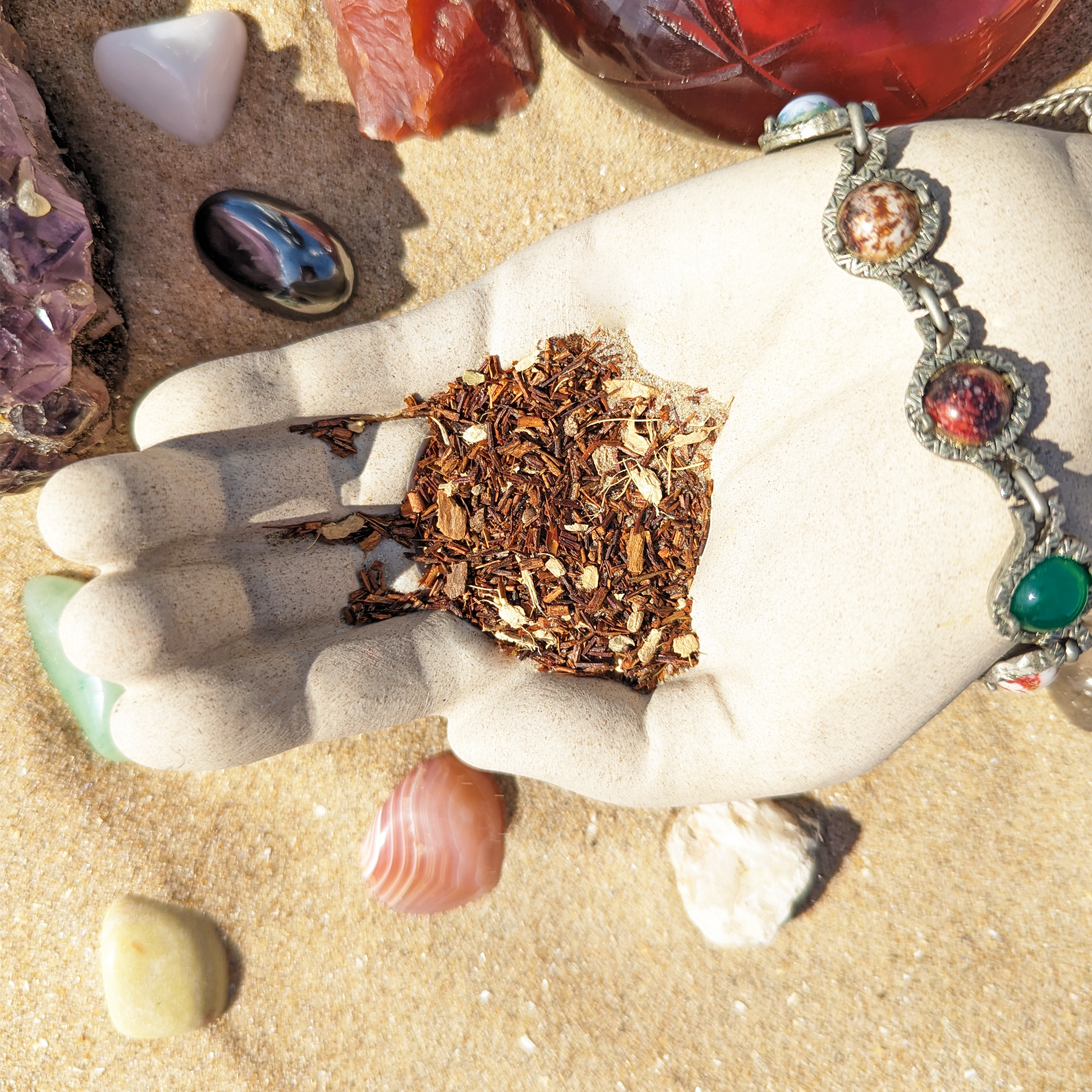 A cement hand cupping  a blend of rooibos and various spices, with a simple piece of jewelry on the wrist.