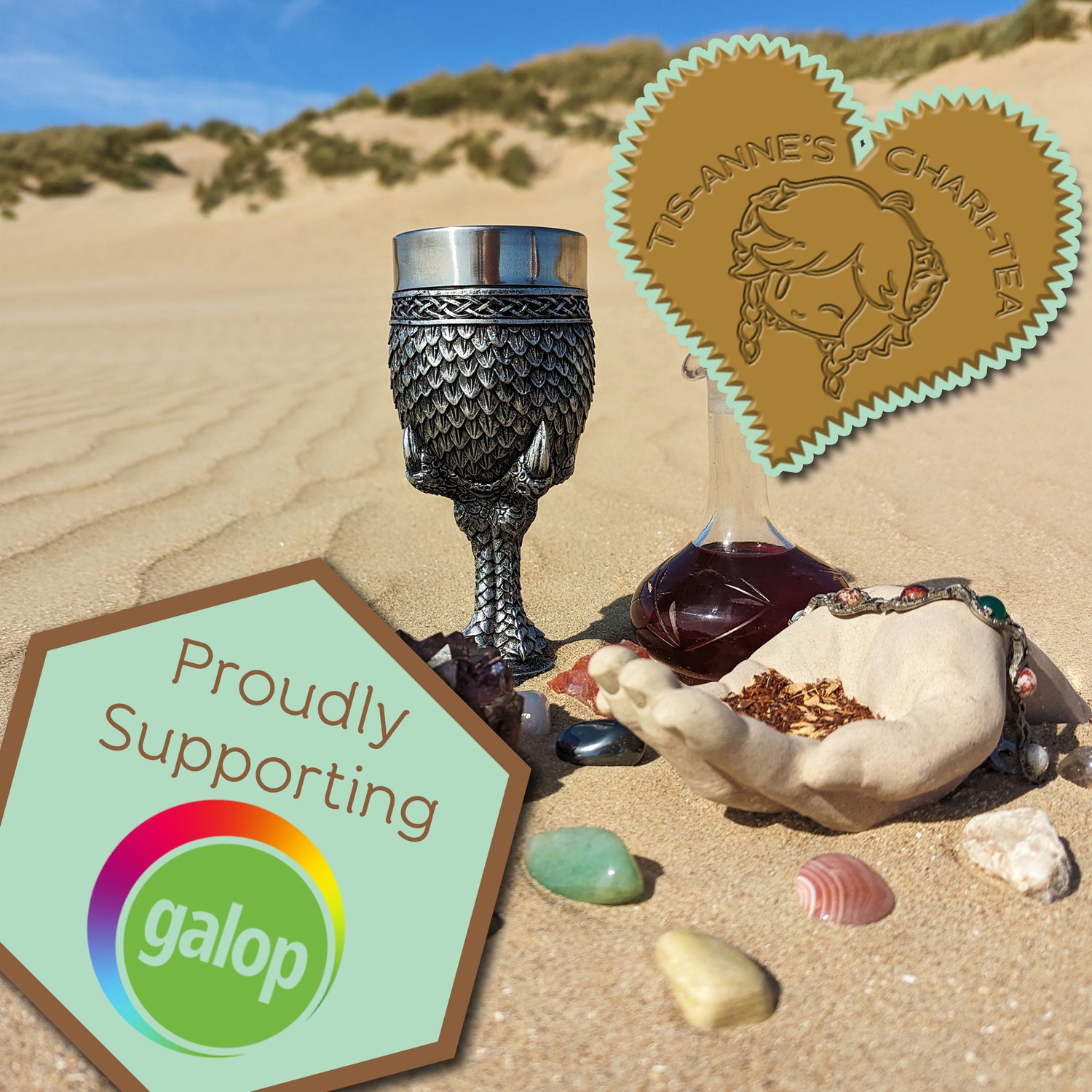A goblet covered in silver dragon scales next to a tall-necked glass bottle filled with a dark red infusion. They are half-buried in the sand, with a blue sky above. A heart-shaped badge in one corner reads "Tis-Anne's Chari-Tea", and another emblem reads "Proudly Supporting" with the Galop logo.