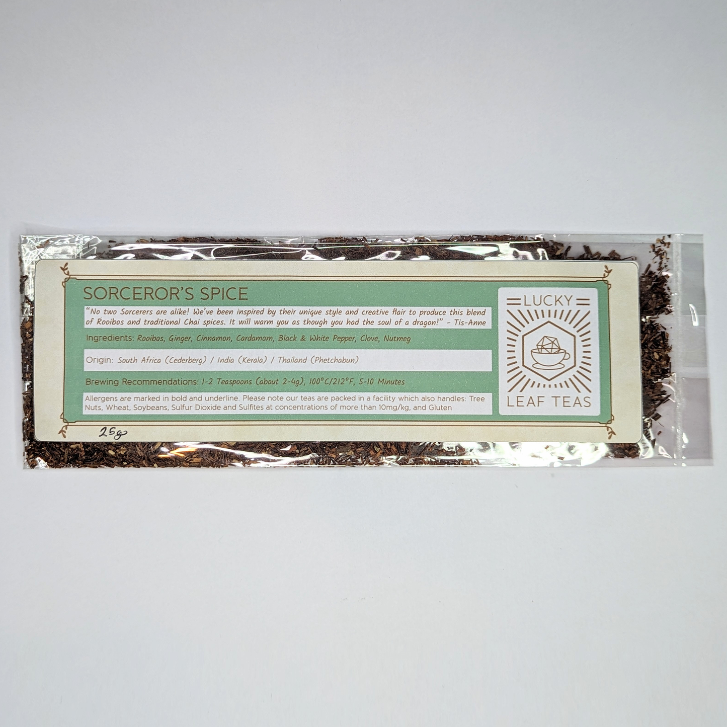 A slim, see-through package containing 25g of Sorcerer’s Spice: an infusion blend of Rooibos and spices. A label with the name, ingredients, origin and brewing recommendations is printed on the front, next to the Lucky Leaf Teas Logo.