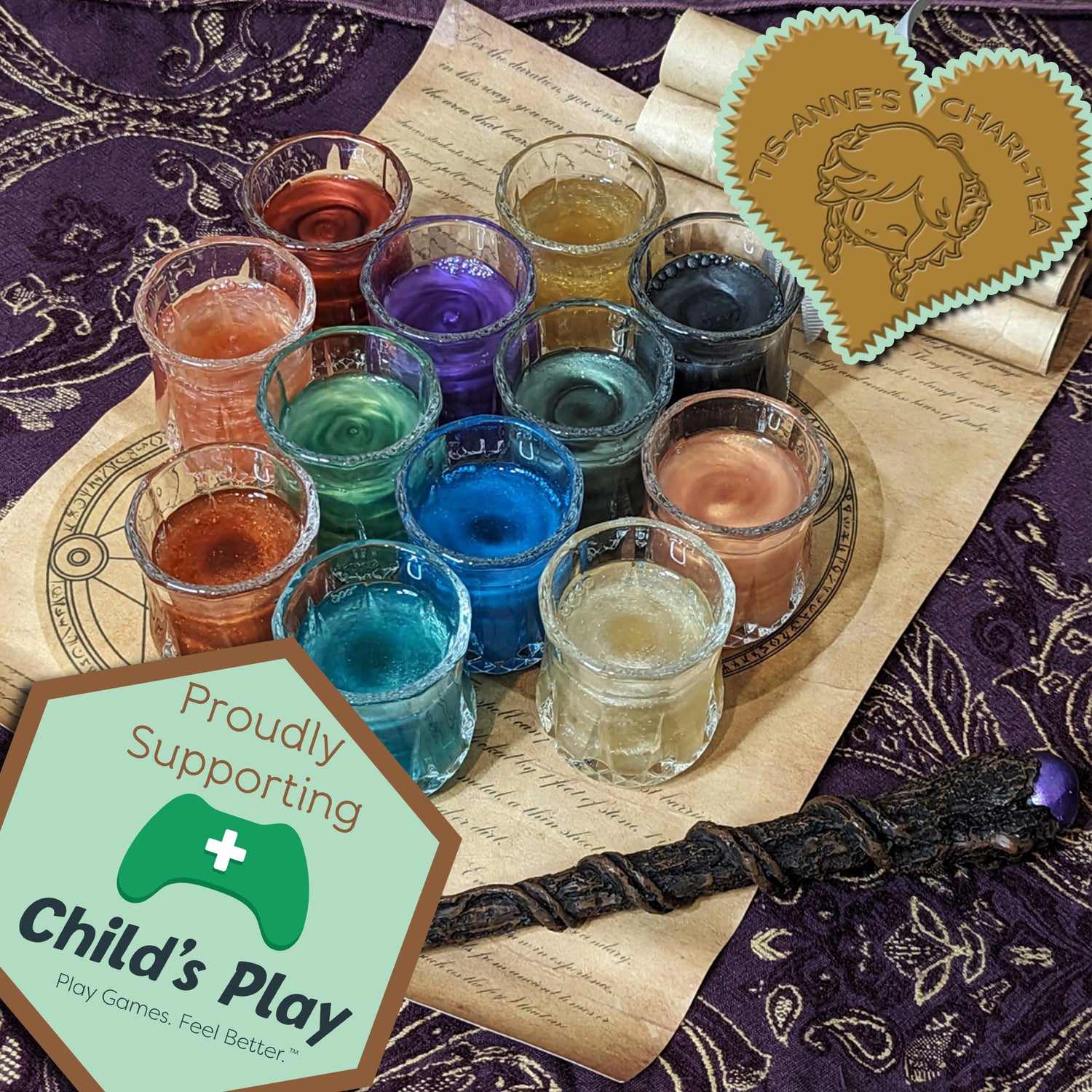 A set of twelve shot glasses on top of a spell scroll. Each one holds glittering liquid in a different colour.
A heart-shaped badge in one corner reads "Tis-Anne's Chari-Tea", and an emblem in the other reads "Proudly Supporting Child's Play. Play Games. Feel Better."